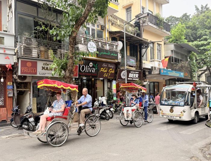 Du khách nước ngoài tham quan phố cổ Hà Nội bằng xe xích lô.