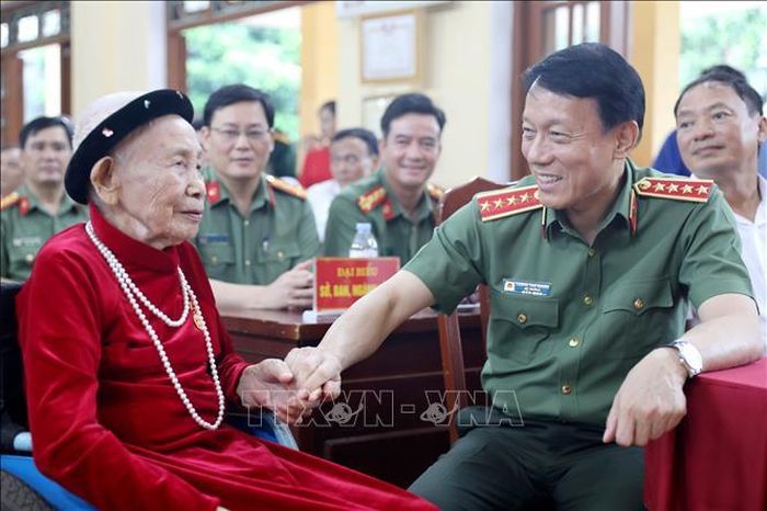Ủy viên Bộ Chính trị, Bộ trưởng Bộ Công an Lương Tam Quang chúc mừng đảng viên Trần Thị Viển nhận Huy hiệu 80 năm tuổi Đảng. Ảnh: Thế Duyệt/TTXVN