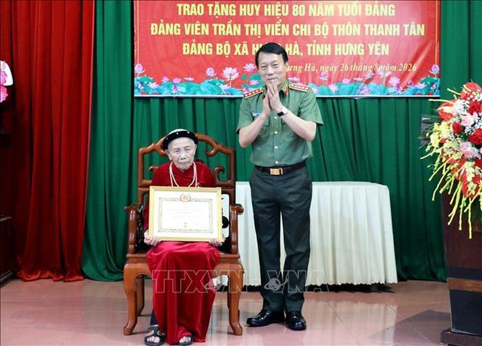 Ủy viên Bộ Chính trị, Bộ trưởng Bộ Công an Lương Tam Quang trao tặng Huy hiệu 80 năm tuổi Đảng cho đảng viên Trần Thị Viển. Ảnh: Thế Duyệt/TTXVN