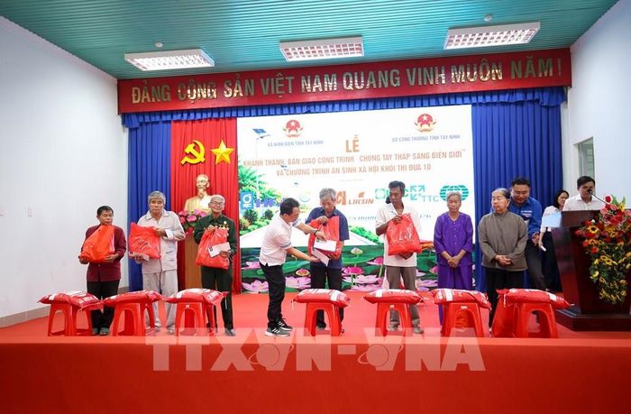 Đại diện các đơn vị đồng hành trao quà cho các hộ gia đình chính sách có hoàn cảnh khó khăn tại xã Ninh Điền, tỉnh Tây Ninh. Ảnh: Giang Phương - TTXVN