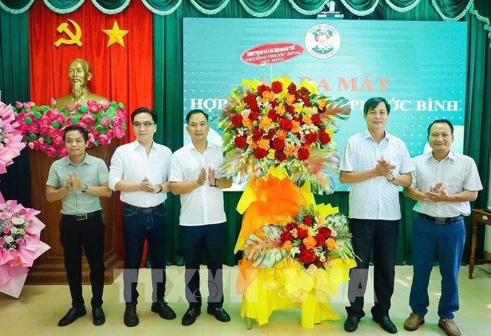 Lãnh đạo phường Phước Bình tặng hoa chúc mừng Hợp tác xã Điều Phước Bình. Ảnh: K GỬIH - TTXVN