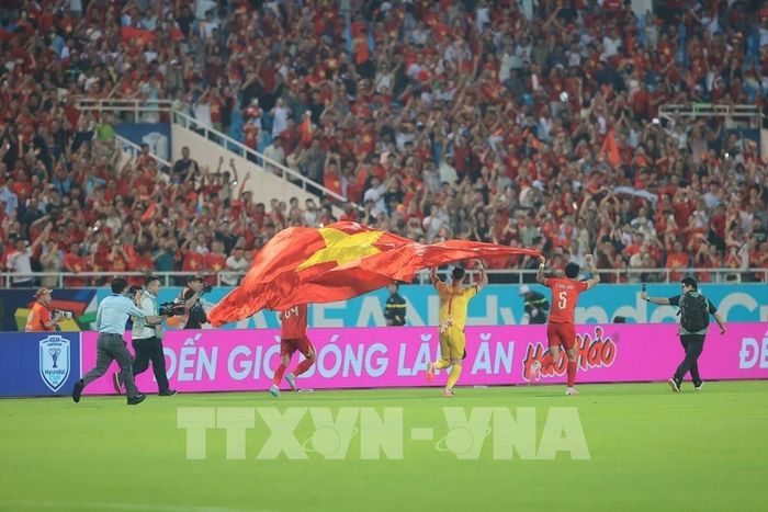 Thủ môn Lê Giang Patrik cùng đồng đội giương cao lá quốc kỳ Việt Nam chạy quanh sân sau khi trận đấu kết thúc. Ảnh: Minh Quyết - TTXVN 