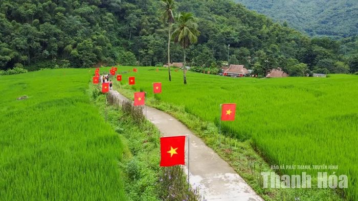 Nhìn từ trên cao, con đường cờ uốn lượn giữa những mái nhà, ruộng nương và triền núi, tạo nên bức tranh thanh bình của bản làng vùng cao.