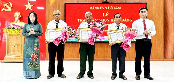 Bí thư Đảng ủy, Chủ tịch HĐND xã Ô Lâm Mai Thị The (bên trái) và Phó Bí thư Thường trực Đảng ủy xã Ô Lâm Tiêu Đình Hiếu Nhân Trung trao Huy hiệu Đảng cho các đảng viên.
