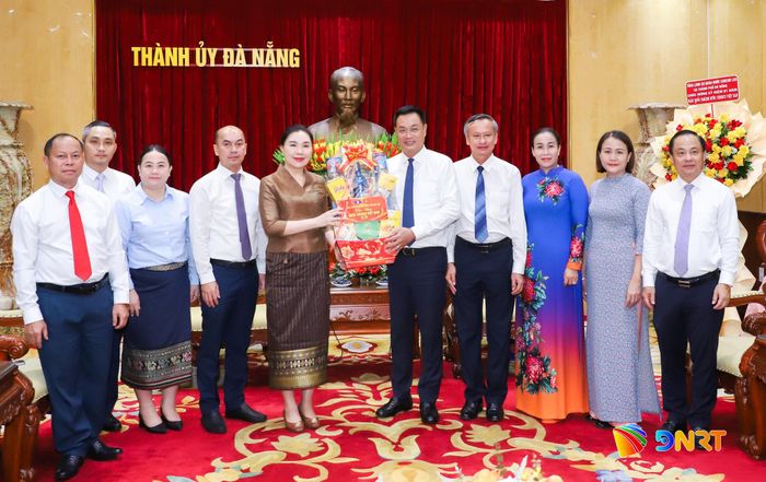 Tổng Lãnh sự Vonkham Chuengmanivong (thứ 5, bên trái sang) tặng quà lãnh đạo thành phố. Ảnh: NGỌC PHÚ