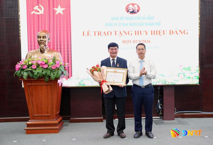 Chủ tịch UBND thành phố Nguyễn Mạnh Hùng (bên phải) trao tặng Huy hiệu 45 năm tuổi Đảng cho đảng viên Võ Xuân Tiến, sinh hoạt tại Đảng bộ Đại học Đà Nẵng. Ảnh: THÀNH CÔNG