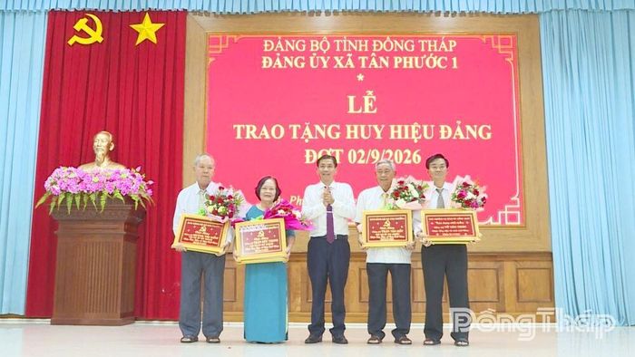 Đồng chí Phạm Văn Hoàng, Bí thư Đảng ủy, Chủ tịch HĐND xã Tân Phước 1 trao Huy hiệu Đảng và tặng quà cho các đảng viên.