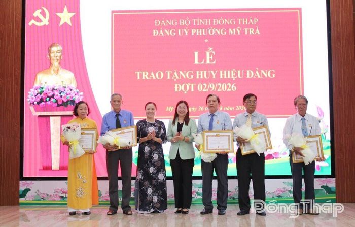 Đồng chí Trần Thị Quý (thứ 3 từ trái sang) và đồng chí Đỗ Thị Thanh Trang trao Huy hiệu Đảng và tặng hoa chúc mừng cho các đảng viên.