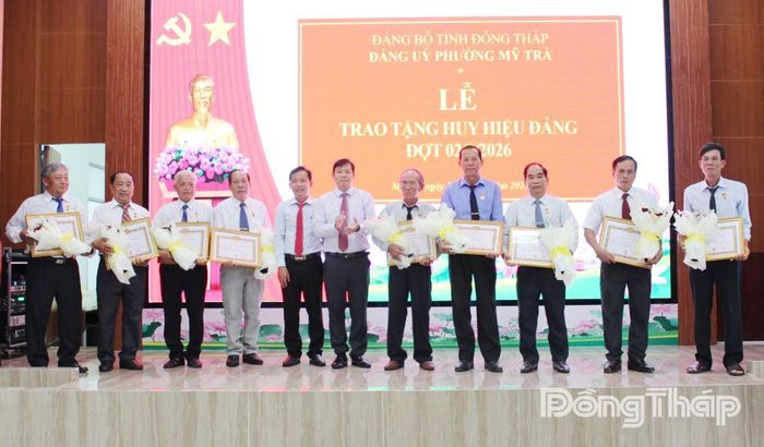 Đồng chí Nguyễn Phước Cường, Phó Bí thư Đảng ủy, Chủ tịch UBND phường Mỹ Trà (thứ 6 từ phải sang) trao Huy hiệu Đảng cho các đảng viên.