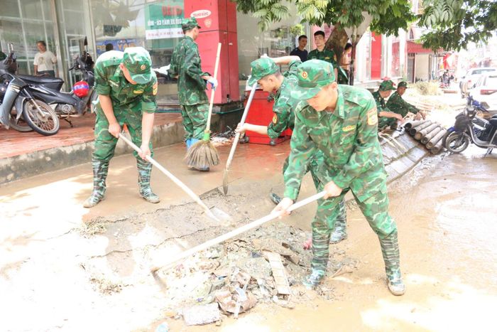 Cán bộ, chiến sĩ Đồn Biên phòng Pò Mã hỗ trợ người dân dọn dẹp vệ sinh môi trường sau bão