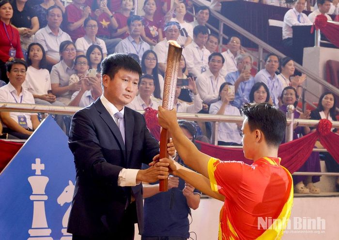 Đồng chí Trần Huy Tuấn, Ủy viên Trung ương Đảng, Bí thư Tỉnh ủy nhận ngọn đuốc từ VĐV tiêu biểu Phạm Minh Quân, châm Đài đuốc Đại hội.