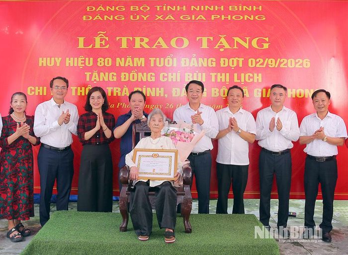 Đồng chí Phó Bí thư Tỉnh uỷ, Chủ tịch UBND tỉnh Nguyễn Thanh Bình và các đại biểu chụp ảnh lưu niệm cùng đảng viên Bùi Thị Lịch.