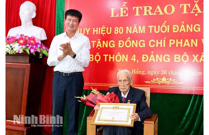 Đồng chí Bí thư Tỉnh ủy Trần Huy Tuấn trao tặng Huy hiệu 80 năm tuổi Đảng và tặng hoa chúc mừng đồng chí Phan Văn Phổ, Chi bộ thôn 4, Đảng bộ xã Xuân Hồng.