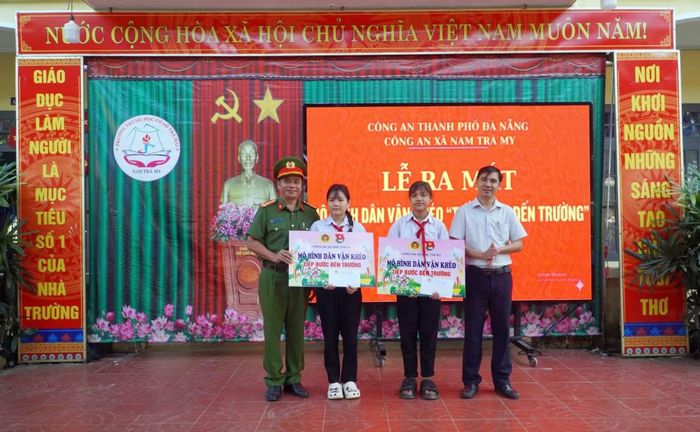 Cán bộ Công an xã Nam Trà My tặng quà các em học sinh có hoàn cảnh khó khăn hiếu học.