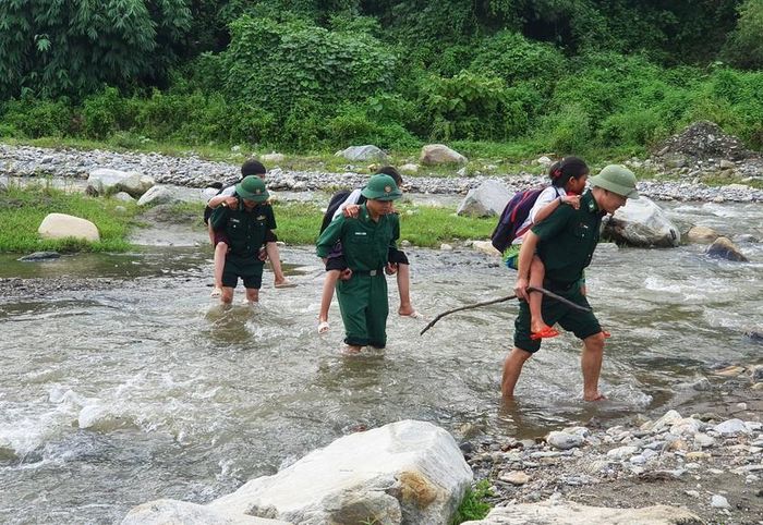 Bộ đội Biên phòng Lào Cai cõng các em học sinh qua suối đến lớp học. Ảnh: Trung Dũng