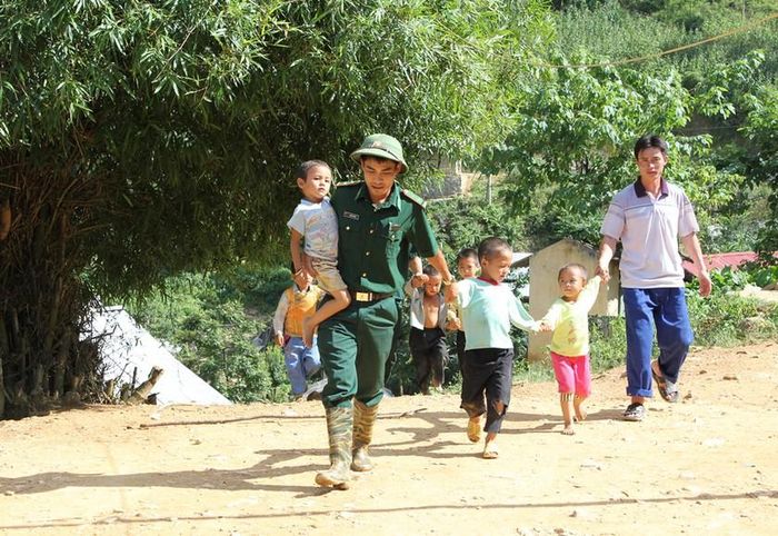 Bộ đội Biên phòng cùng người dân biên giới đưa các cháu nhỏ vượt núi băng rừng đến lớp học chữ. Ảnh: Trung Dũng