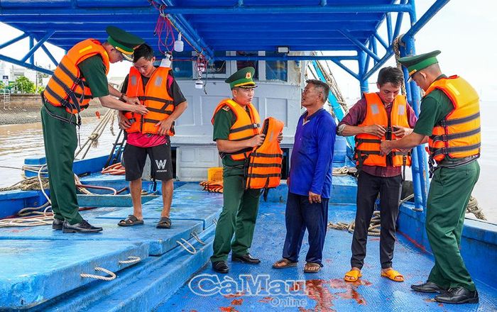 Cán bộ, chiến sĩ Ðồn Biên phòng Gành Hào hướng dẫn ngư dân sử dụng áo phao đúng cách.