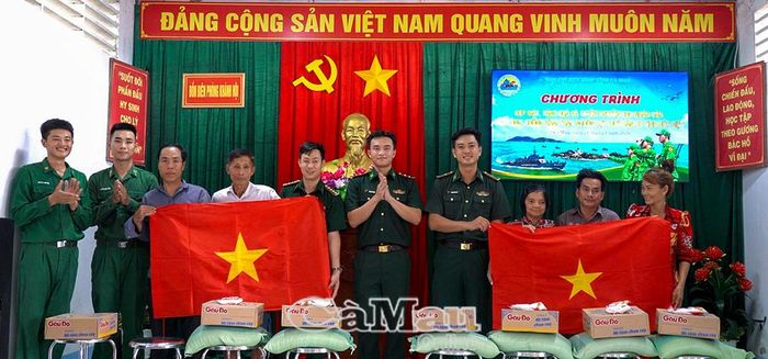 Trung tá Nguyễn Thanh Hải, Đồn trưởng Đồn Biên phòng Khánh Hội (bên phải) và Trung tá Đoàn Văn Nghĩa, Chính trị viên phó Đồn Biên phòng Khánh Hội, trao tặng cờ Tổ quốc và ảnh Bác Hồ cho người dân.