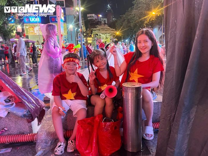 Càng gần giờ thi đấu, dòng người quanh phố đi bộ Nguyễn Huệ càng đông. Nhiều nhóm cổ động viên mặc áo đỏ, mang theo cờ và băng rôn tạo nên không khí sôi động.