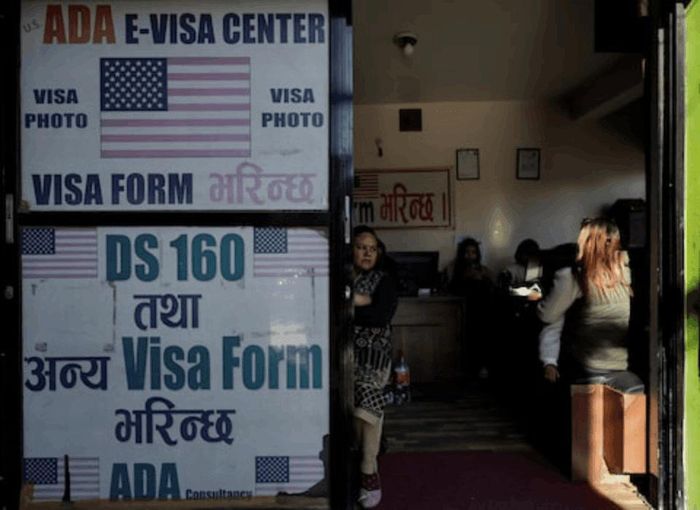 Một người phụ nữ bế con chờ điền đơn xin visa Mỹ tại một công ty tư vấn hỗ trợ làm thủ tục visa ở Kathmandu, Nepal. Ảnh: REUTERS