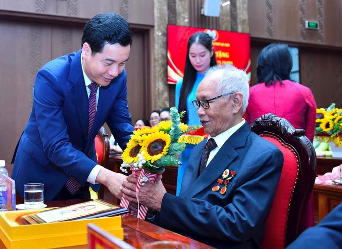 Chánh Văn phòng Thành ủy Hà Nội Nguyễn Việt Hà tặng hoa chúc mừng đảng viên được tặng Huy hiệu Đảng. Ảnh: Nhóm phóng viên