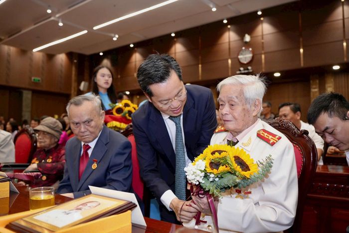 Trưởng ban Tổ chức Thành ủy Hà Nội Vũ Đăng Định tặng hoa chúc mừng đảng viên được tặng Huy hiệu Đảng. Ảnh: Nhóm phóng viên