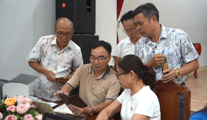 Ông Nguyễn Hữu Hạnh, Tổ trưởng tổ dân phố Sơn Lộc, phường Tùng Thiện hướng dẫn người dân sử dụng các ứng dụng trên nền tảng số. Ảnh Đ. Đạt