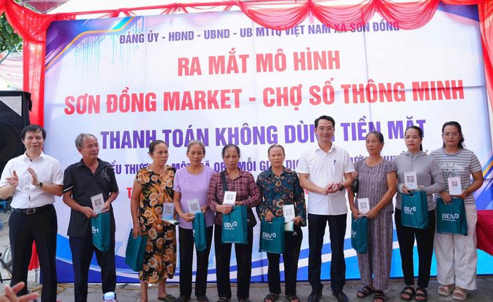 Các tiểu thương nhận mã QR thanh toán. Ảnh: NS