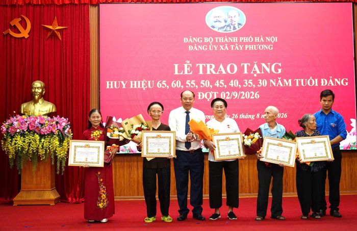 Chủ tịch UBND xã Tây Phương Cấn Văn Hương trao Huy hiệu Đảng cho các đảng viên. Ảnh: Hữu Dũng.