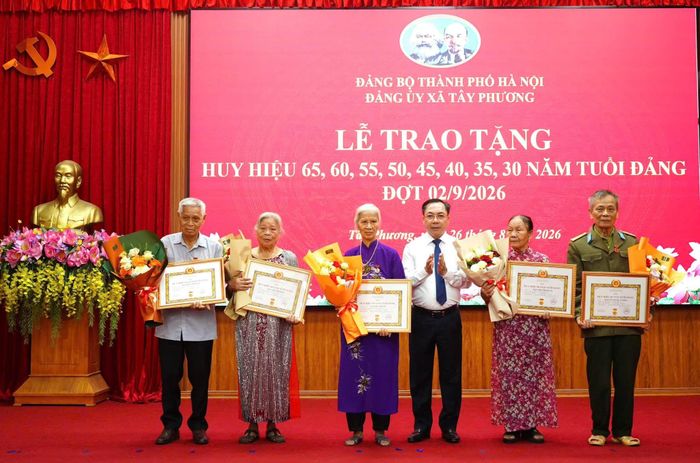 Bí thư Đảng ủy xã Tây Phương Nguyễn Mạnh Hồng trao Huy hiệu Đảng cho các đảng viên. Ảnh: Hữu Dũng