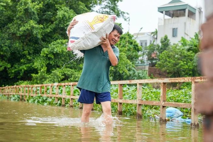 Nhiều người dân lội nước, mang vác hàng hoá qua cầu.