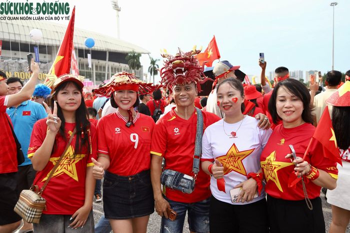 Tại khu vực quanh sân, nhiều nhóm cổ động viên tập trung chụp ảnh, giao lưu và hô vang các khẩu hiệu cổ vũ đội tuyển. Một số người tranh thủ mua thêm cờ, áo đấu và các vật dụng phục vụ việc cổ vũ. (Ảnh Thành Long)