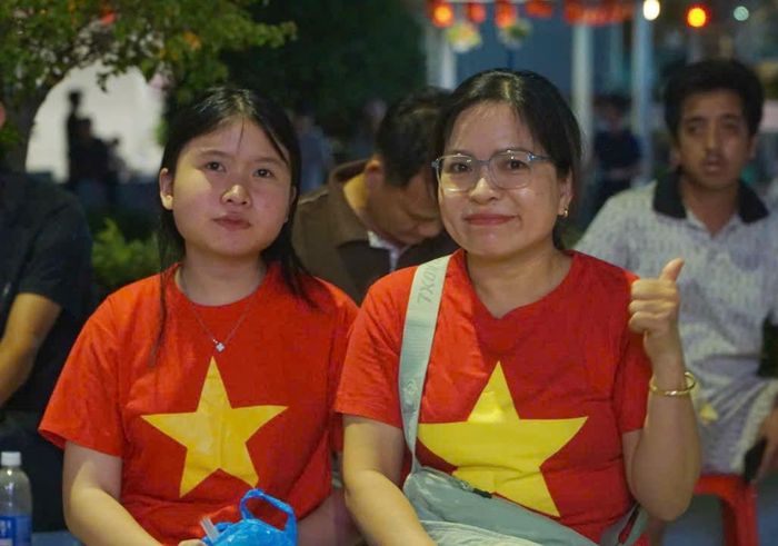Chị Minh cùng con gái mặc áo cờ đỏ sao vàng cổ vũ đội tuyển Việt Nam. Ảnh: Nguyễn Thuận.