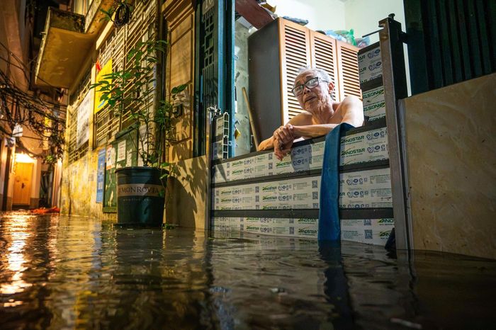  Sau nhiều năm sống chung với mưa ngập mỗi khi mưa lớn đổ xuống, ông Nguyễn Hữu Hứng (72 tuổi, sống ở ngõ 42 Giang Văn Minh) đánh giá năm nay nước ngập rút xuống nhanh hơn do có các công nhân thuộc Xí nghiệp Thoát nước số 1 thiết lập và vận hành hệ thống máy bơm dã chiến công suất lớn ngay tại hố ga chính của ngõ. Theo ông Hứng, tình trạng ngập úng xảy ra chủ yếu do nền đường tại đây thấp hơn. Ảnh: Đinh Hà.