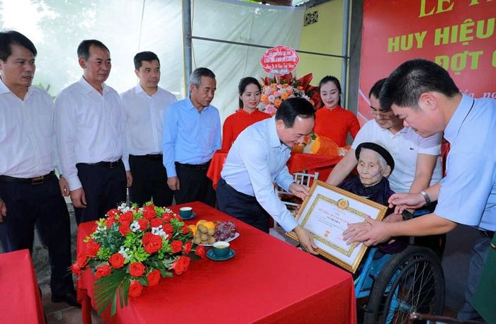 Ủy viên Bộ Chính trị, Bí thư Trung ương Đảng, Trưởng Ban Tuyên giáo Trung ương Trịnh Văn Quyết trao và gắn Huy hiệu 80 năm tuổi Đảng cho bà Lê Thị Thủy, ở thôn Trung Thôn, xã Thọ Long
