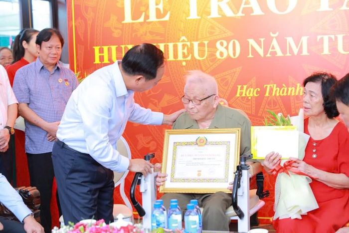Ủy viên Bộ Chính trị, Bí thư Trung ương Đảng, Trưởng Ban Tuyên giáo Trung ương Trịnh Văn Quyết trao và gắn Huy hiệu 80 năm tuổi Đảng cho ông Trịnh Khắc Thuần, sinh năm 1927, ở phường Hạc Thành