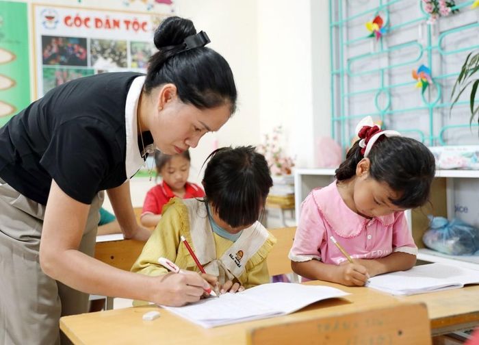 Giáo viên Trường Phổ thông Dân tộc Bán trú Tiểu học và Trung học cơ sở Thu Lũm hướng dẫn học sinh lớp 1 tập viết chữ. Ảnh: Quý Trung - TTXVN