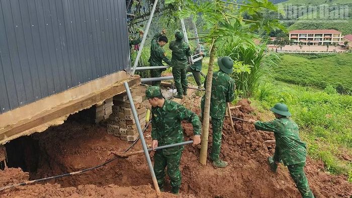 Cán bộ, chiến sĩ Đồn Biên phòng Cửa khẩu quốc tế Lóng Sập giúp hộ gia đình tại bản Bó Sập khắc phục hậu quả sạt lở đất. (Ảnh: QUÀNG HÙNG)
