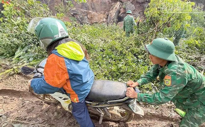 Cán bộ, chiến sĩ Đồn Biên phòng Chiềng Tương hỗ trợ người dân qua lại khu vực đoạn đường bị sạt lở. (Ảnh: QUÀNG HÙNG)