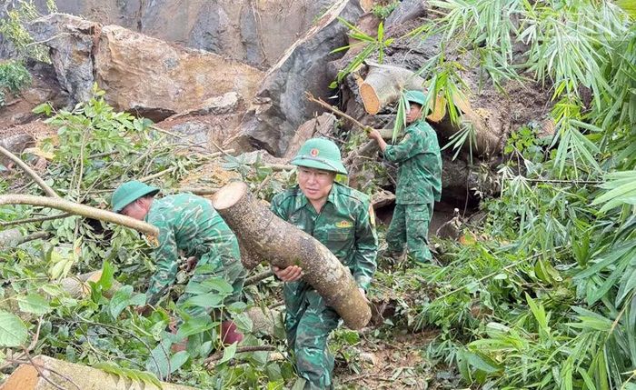 Cán bộ, chiến sĩ Đồn Biên phòng Chiềng Tương dọn dẹp cây cối, đất đá bị đổ chắn ngang đường tại xã Lóng Phiêng. (Ảnh: QUÀNG HÙNG)