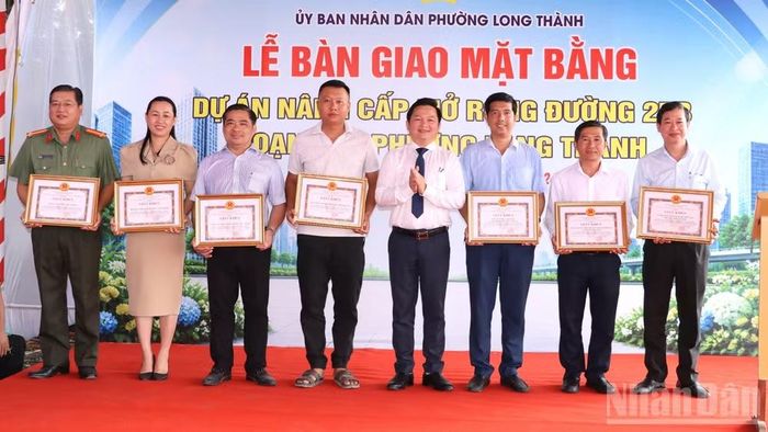 Bí thư Đảng ủy, Chủ tịch Hội đồng nhân dân phường Long Thành Nguyễn Hữu Nguyên trao khen thưởng các tập thể có nhiều thành tích xuất sắc trong thực hiện công tác bồi thường, hỗ trợ tái định cư Dự án nâng cấp, mở rộng đường 25B. (Ảnh: THIÊN VƯƠNG)