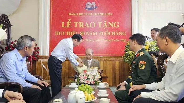 Đồng chí Trịnh Văn Quyết trao Huy hiệu Đảng và tặng hoa chúc mừng đảng viên Nguyễn Xuân Trớc. (Ảnh: MAI LUẬN)