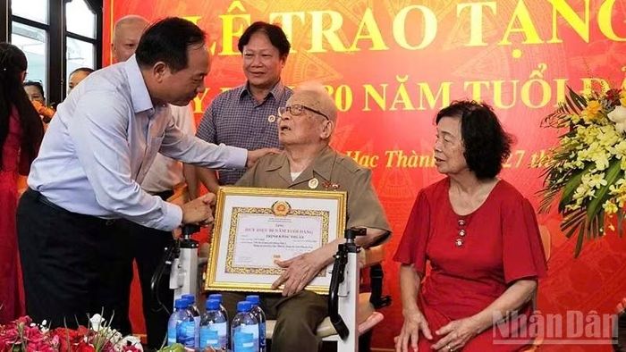 Đồng chí Trưởng Ban Tuyên giáo Trung ương trao Huy hiệu 80 năm tuổi Đảng cho cụ Trịnh Khắc Thuần. (Ảnh: MAI LUẬN)