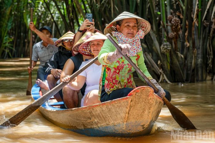 Xuồng do người dân địa phương chèo, len lỏi qua những con rạch nhỏ rợp bóng dừa nước, hai bên là vườn cây ăn trái xanh mát.