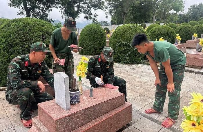 Trung tá Đào Xuân Trường (đầu tiên bên phải) cùng Trung tá Nguyễn Văn Ngọc đang hướng dẫn các chiến sĩ cách trát mạch hoàn nguyên trên các phần mộ tại Nghĩa trang Liệt sĩ Tông Khao. (Ảnh: LÊ LAN)