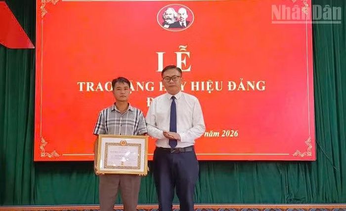 Đồng chí Vi Tuấn Bảo, Bí thư Đảng ủy xã Lóng Phiêng chuyển trao Huy hiệu 60 năm tuổi Đảng được truy tặng cho thân nhân đảng viên Lìa Xuân Tơ, Chi bộ bản Chiềng Tương. (Ảnh: QUỐC TUẤN)