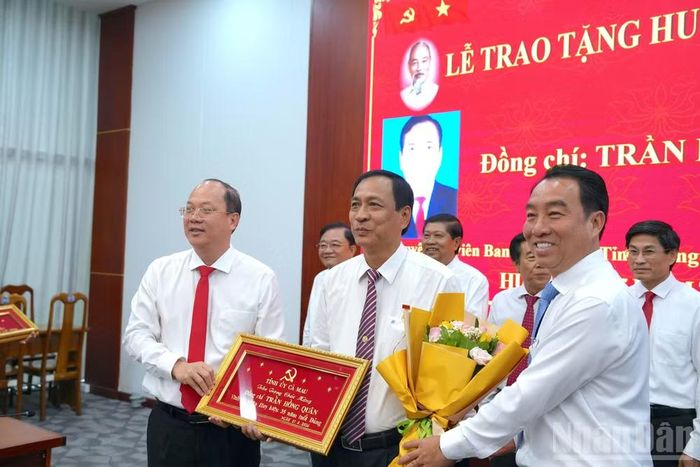 Bí thư Tỉnh ủy Cà Mau Nguyễn Hồ Hải (bìa trái) và Chủ tịch Ủy ban nhân dân tỉnh Lữ Quang Ngời (bìa phải) trao Huy hiệu Đảng 35 năm và tặng hoa chúc mừng cho đồng chí Trần Hồng Quân, nguyên Ủy viên Ban Thường vụ Tỉnh ủy, nguyên Bí thư Thành ủy Cà Mau. (ảnh HỮU TÙNG).