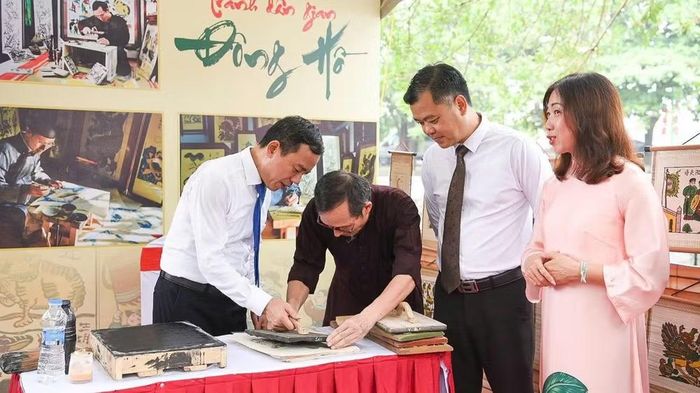 Các đại biểu trải nghiệm làm tranh dân gian Đông Hồ trong khuôn viên cụm đình, đền, chùa Đồng Kỵ. (Ảnh AN TRÂN)