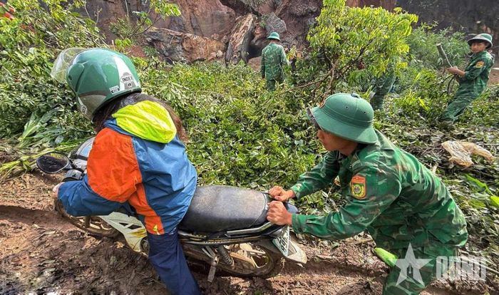 Cán bộ, chiến sĩ Đồn Biên phòng Chiềng Tương (Ban chỉ huy Bộ đội Biên phòng tỉnh Sơn La) hỗ trợ người dân qua lại khu vực đoạn đường bị sạt lở. Ảnh: QUÀNG HÙNG
