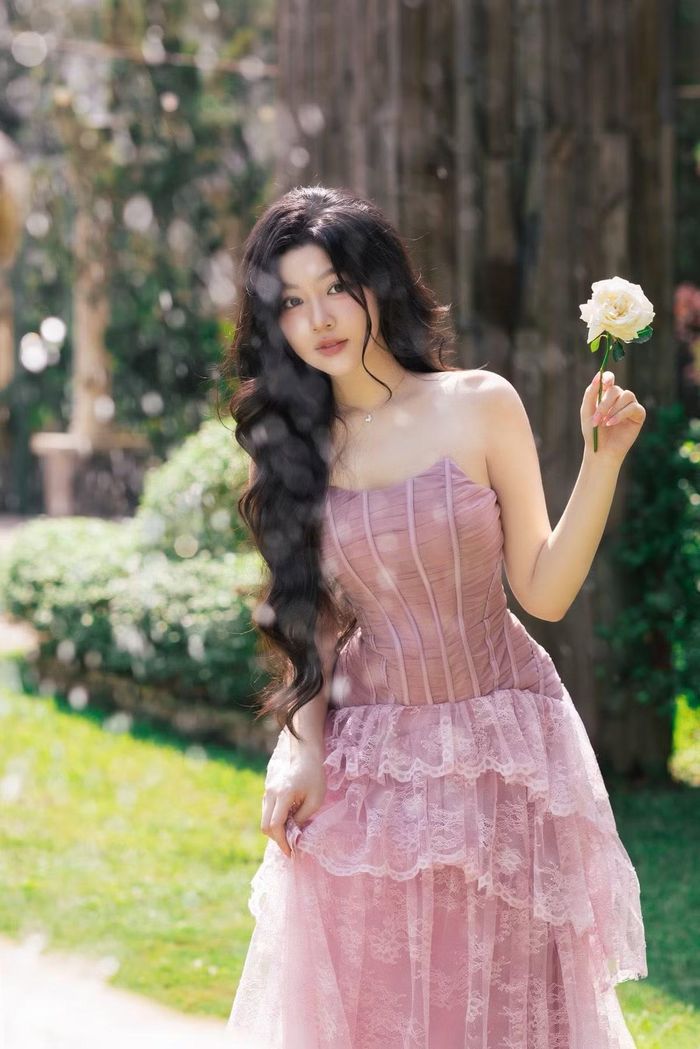 Lọ Lem chọn váy quây hồng với thân corset ôm dáng và chân váy ren xếp tầng. Thiết kế làm nổi bật bờ vai và vóc dáng mảnh mai. Tóc dài uốn sóng, trang điểm tông hồng đồng điệu với trang phục, tạo hình ảnh ngọt ngào hơn. (Ảnh: FB Mai Thảo Linh)